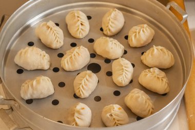 Hamur hamurundan yapılmış çiğ manti ya da wonton bir buharlı tencereye konur. Ev yapımı yemek. Yakın plan..