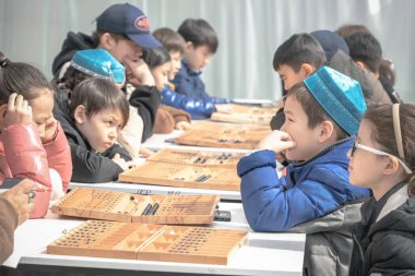 Almaty, Kazakistan - 23 Mart 2024. Sokaktaki çocuklar Kazak ulusal masa oyunu Togyz kumalak 'ı oynuyor.