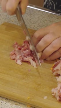 Şef ahşap bir kesme tahtasıyla çiğ et şeritlerini kıyma haline getirir. Aşçılık ve mutfak sahneleri.