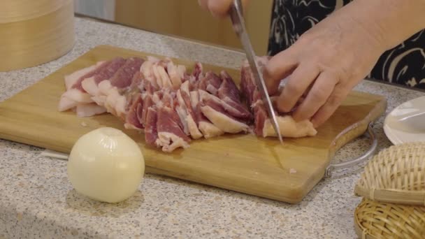 シェフは生肉のストリップを木製の切断板に採取した肉に切断します 料理とキッチンシーン — ストック動画
