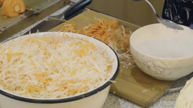 Aşçı tuz çözeltisi hazırlar ve fermantasyon için ince doğranmış lahana ve havuç koyar. Ev yapımı yemek.