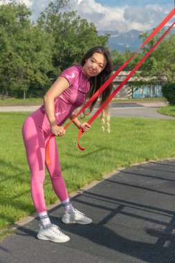 Sokak sporları alanında lastik genişleticiyle egzersiz yapan Asyalı bir kız. Spor ve Rekreasyon.