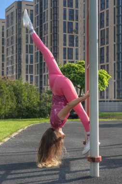 Güzel bir Asyalı kız açık hava spor sahasındaki metal bir duvarda jimnastik egzersizleri yapıyor. Sağlıklı yaşam tarzı