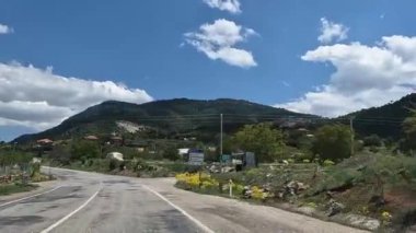 Bursa, Trkiye 15 Mayıs 2022. Kırsal bir yolda mavi gökyüzü ve bulutların arka planına karşı araba sürmek. Birinci şahıs