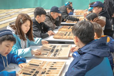 Almaty, Kazakhstan - March 23, 2024. Children on the street play the Kazakh national board game Togyz kumalak clipart