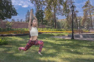 Güzel Asyalı kız parkta çimlerde yoga yapıyor. Fitness. Sağlıklı yaşam tarzı