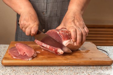 Aşçı bir parça çiğ eti biftek ya da pirzola olarak bıçakla keser. Yakın plan.