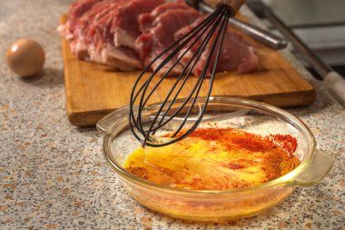 A chef whisks raw eggs, salt, red pepper and paprika for seasoning before frying pounded pieces of beef fillet. Close-up clipart