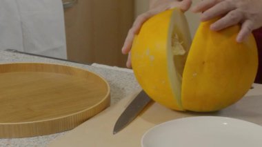 Kadının eli karpuzu bıçakla keser ve tohumları kaşıkla temizler.