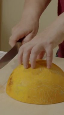 Kadın, kavunun yarısını bıçakla dilimliyor.