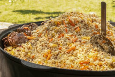 Açık ateşte büyük bir kazanda pişirilmiş etli pilav. Sokak yemeği. Yakın plan.
