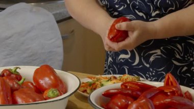 Kırmızı dolma biberden çekirdek ve tohumları çıkarmak için bıçak kullanan kadın.. 