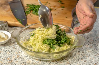 Şef, cam bir tabakta kaşıkla krep yapmak için kabak hamuruyla ince doğranmış sebzeleri rendeleyip rendeleyecek. Yakın plan.