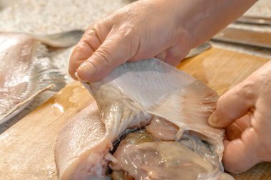 Şef daha fazla pişirmek için taze balık derisini yüzüyor. Yakın plan.