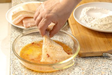 Şef, kızarmadan önce çiğ yumurta, tuz ve kırmızı biber karışımından oluşan bir balık parçasını irtibatın içine batırır.