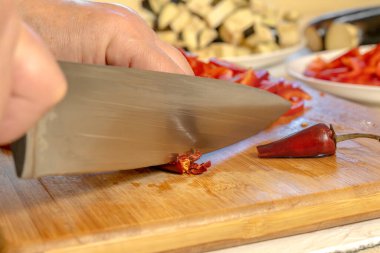 Kesme tahtasındaki kırmızı kırmızı biberi kesiyorum. Yakın plan.