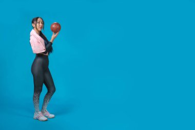 Spor giyimli Asyalı kız spor topuyla egzersiz yapıyor. İzole edilmiş mavi arka plan. Sağlıklı yaşam tarzı kavramı