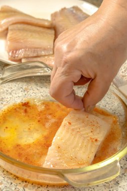 Chef dips a piece of fish into liaison - a mixture of raw eggs, salt, paprika before frying clipart