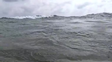 Deniz dalgası sahile doğru yuvarlanıyor ve kamerayı su basıyor.