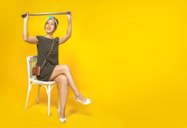 Pin tarzı giyinmiş Asyalı bir kız klasik kamerayla duygusal olarak parlak sarı arka planda film negatiflerine bakıyor. İzole edilmiş. Boşluğu kopyala