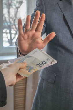Takım elbiseli bir adam avucunu öne uzatıyor ve avrodan para almayı reddediyor. Rüşvetin reddi.