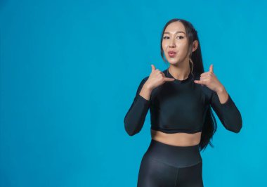 Spor giyim giymiş ince, güzel bir Asyalı kız gülümser ve 