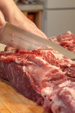 Bir aşçının eli pişirmek için çiğ domuz boynunu bıçakla keser. Yakın plan.