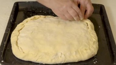 Aşçının eli hamuru çimdikler ve onu fırına koymadan önce pastayı şekillendirir.