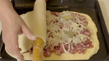 Şef hamurun üst katmanını oklavayla yerleştirir ve etli turtayı boş bırakır..