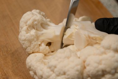 Şef, karnabaharı mutfak tahtasıyla çiçeklere ayırıyor. Yakın plan.