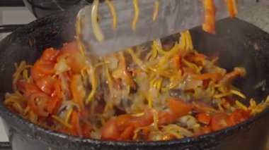        .  Şef, eski dökme demir tavada sebze güveci kızartıyor. Yakın plan.