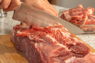 Şef pişirmek için çiğ domuz boynunu bıçakla keser. Yakın plan.