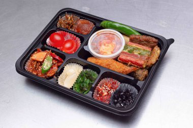 A delicious-looking lunch box with a variety of side dishes, fruits and tempura