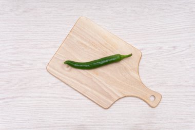 Fresh green chillies plated on a white background