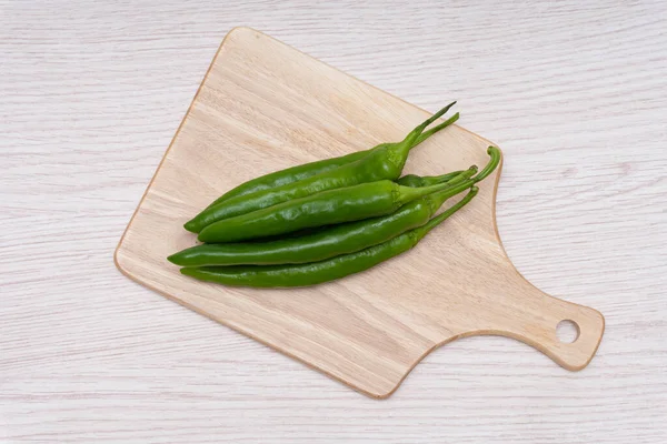 Fresh green chillies plated on a white background