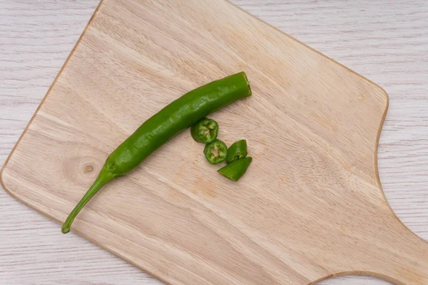 Fresh green chillies plated on a white background