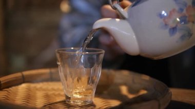 Çay kadehinin şarap masasına dökülmesi yavaş çekimde, sıcak içecek içeceği çay saati..