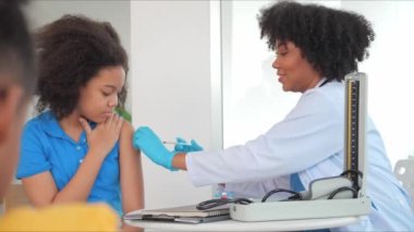 Afro-Amerikalı çocuklar klinikte ya da hastanede aşı oluyorlar. El hemşiresi koruma için aşı enjekte ediyor. Çocuk aşısı kavramı.