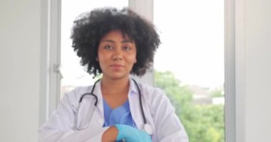 Kendinden emin, gülümseyen Afrikalı siyahi doktor kameraya ve çapraz silahlara bak beyaz önlüklü profesyonel siyah doktor hayat kurtarmaya hazır.