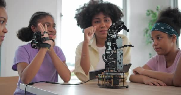 アフリカの黒人の子供たちは学校でロボットアームで遊んでいます グループ学生は手で管理されます テクノロジーとイノベーションの概念 — ストック動画