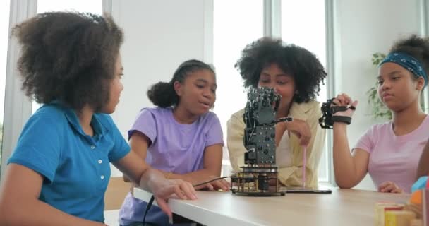アフリカ系黒人の子供たちのグループはロボットアームスクールについて学び 教師はロボット工学教室の小学生を支援している テクノロジーとイノベーションの概念 — ストック動画