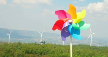 Yüksek rüzgar türbini parkı ve yeşil enerji kavramının panoramik görüntüsüne sahip renkli plastik yel değirmenlerinin hareketi
