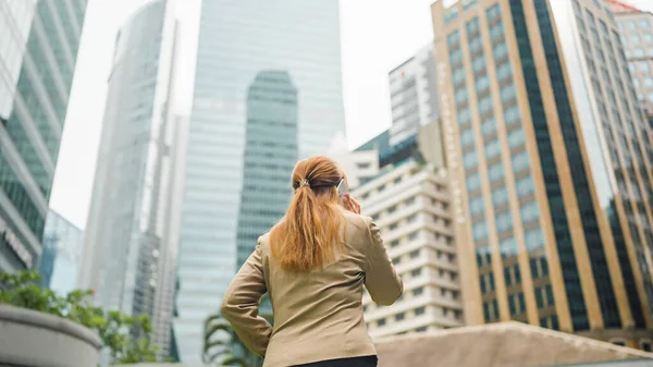スマートフォンと話して街を歩くビジネス女性 — ストック写真