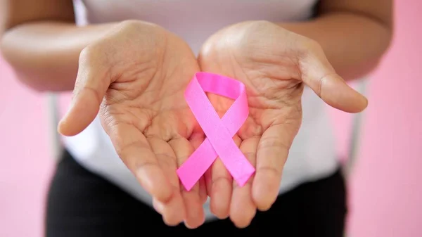 Close up hand holding pink ribbon. Breast cancer awareness month, Pink Day, World Cancer Day, National Cancer Survivor Day