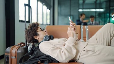 Havaalanı terminalindeki uçuşu beklerken turistler ve yolcular havaalanı koltuğunda yalan söylüyor ve daktilo kullanıyor.