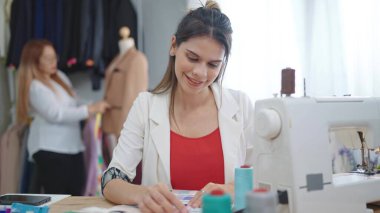 Profesyonel Asyalı kadın moda tasarımcısı. Stüdyo ya da giyim mağazasındaki yeni kıyafet koleksiyonu için fabik renkler seçiyor.