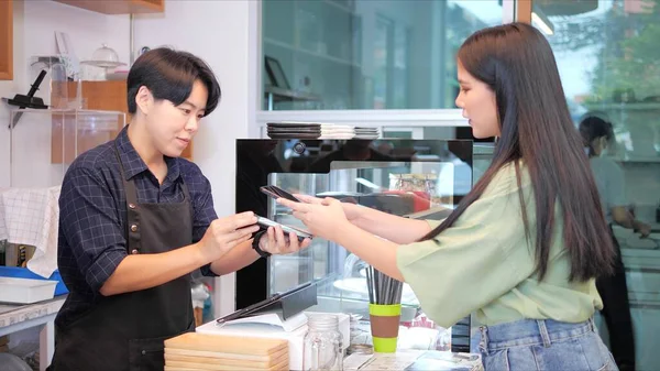 通过智能手机扫描咖啡店或餐馆里另一个智能手机上的Qr代码标签 亚洲女性顾客和咖啡店接受免费数字支付 — 图库照片