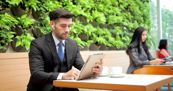 オープンラップトップでカフェレストランに座ってビジネスパートナーと話をする正式な訴訟でハンサムなビジネスマン — ストック写真
