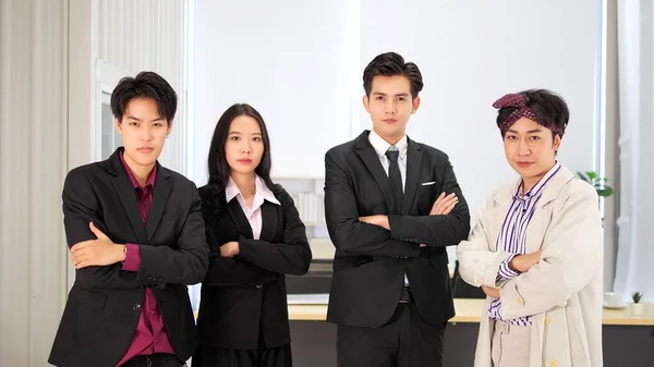 腕を組んで立ってスーツを着た幸せなアジアのビジネスマンのグループが交差し オフィスでカメラを見て — ストック写真