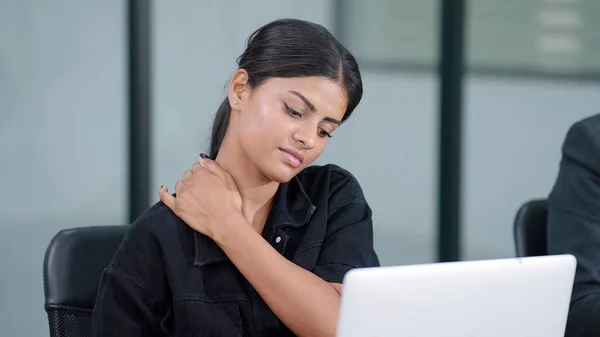 Indian businesswoman sit at workplace experiences severe pain and massaging in neck and exercise. Office syndrome concept